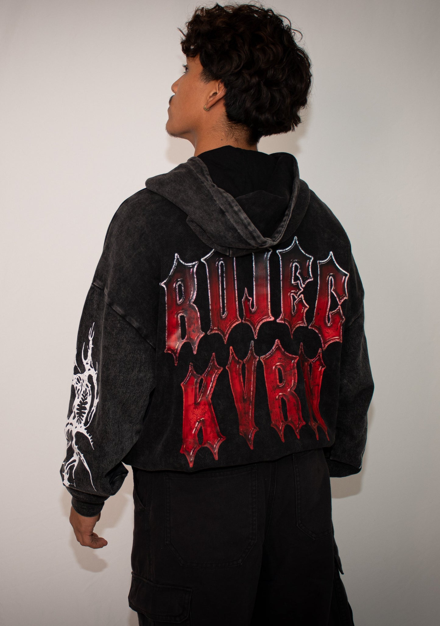 Person wearing a black hoodie with red and white text on the back against a plain background