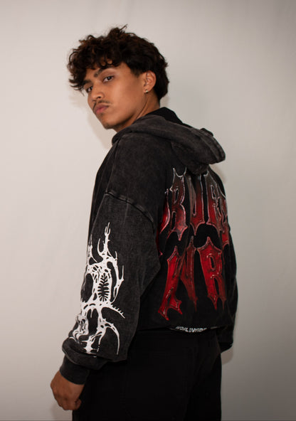Person wearing a black hoodie with red and white designs on a plain background