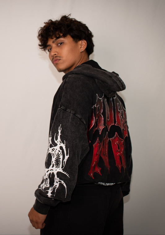 Person wearing a black hoodie with red and white designs on a plain background