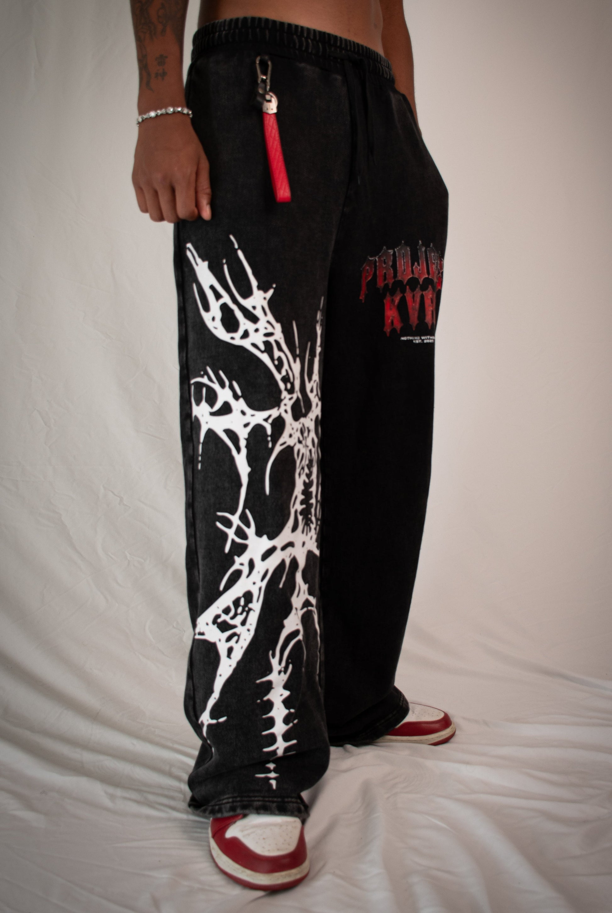 Black pants with white design and red accents on a plain background