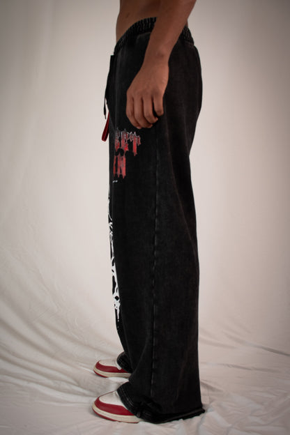 Person wearing black pants with colorful designs on a plain background